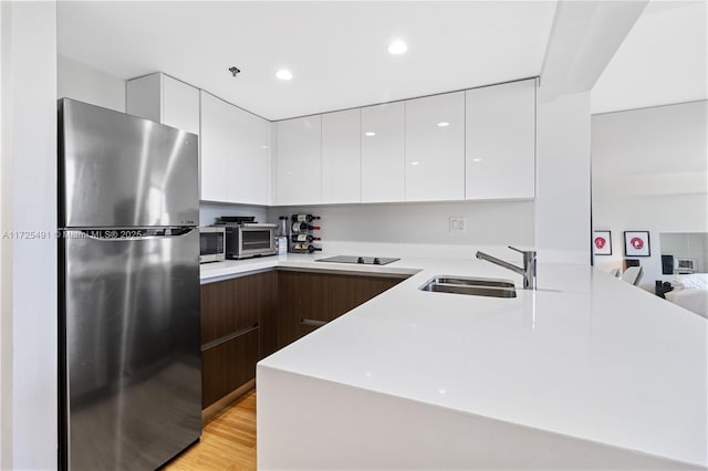 kitchen featuring sink, white cabinetry, light hardwood / wood-style floors, dark brown cabinetry, and appliances with stainless steel finishes