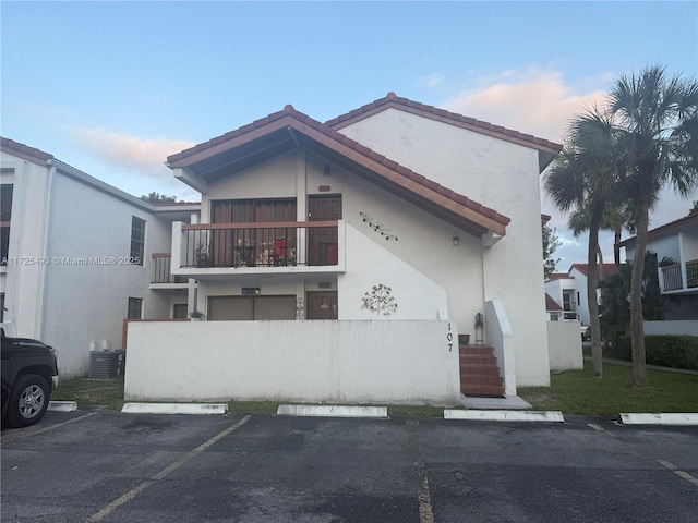 view of front of property with central air condition unit and a balcony