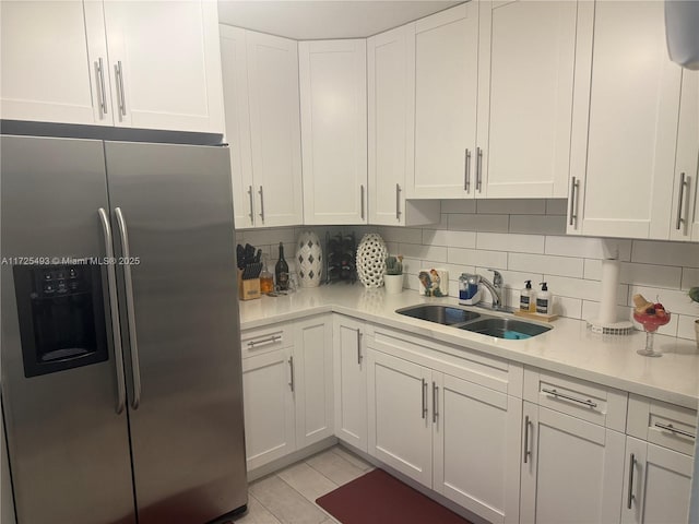 kitchen featuring sink, white cabinets, tasteful backsplash, and stainless steel fridge