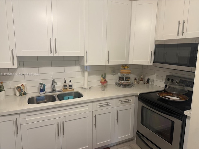 kitchen featuring appliances with stainless steel finishes, white cabinetry, tasteful backsplash, and sink