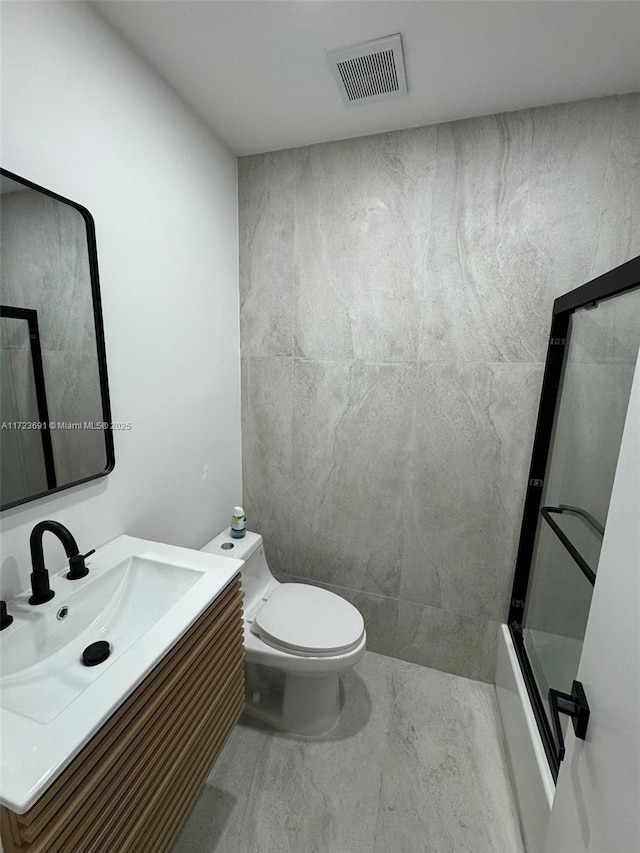 bathroom featuring vanity, a shower with shower door, and toilet