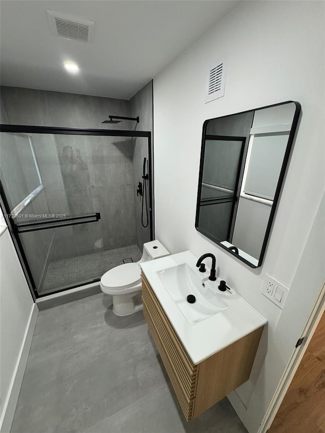 bathroom featuring toilet, vanity, and a shower with shower door