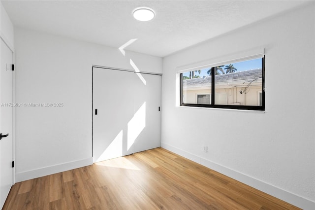 unfurnished bedroom with hardwood / wood-style flooring, a closet, and a textured ceiling