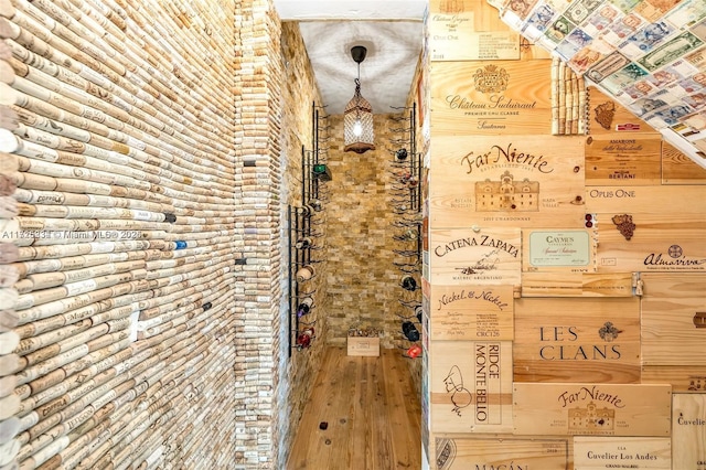 wine area with hardwood / wood-style floors and brick wall