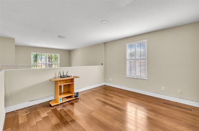 unfurnished room with hardwood / wood-style floors and plenty of natural light