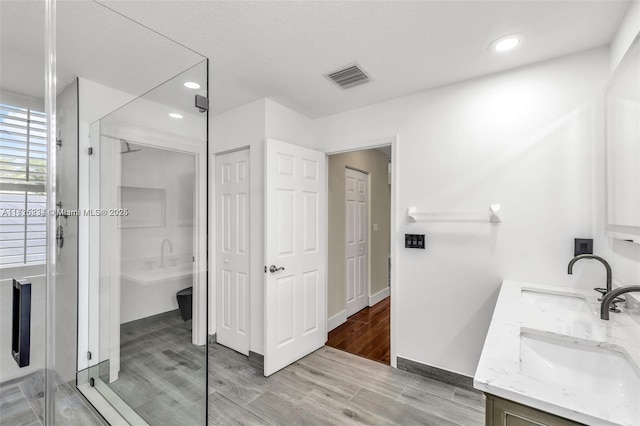 bathroom with a shower with shower door and vanity