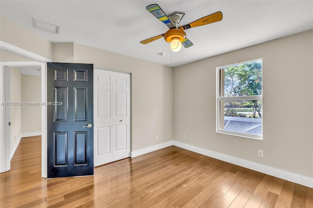 unfurnished bedroom featuring ceiling fan, a closet, and wood-type flooring