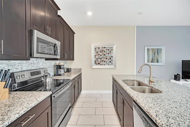 kitchen with sink, light tile patterned floors, backsplash, light stone countertops, and appliances with stainless steel finishes