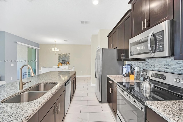 kitchen with sink, hanging light fixtures, light stone counters, and appliances with stainless steel finishes