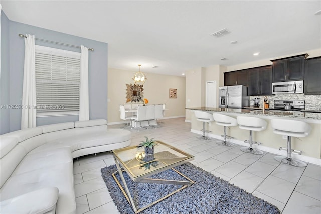 tiled living room featuring sink and a chandelier