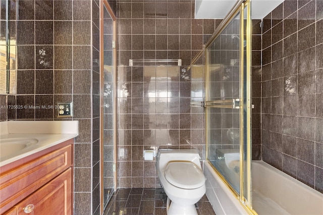 full bathroom with tile patterned flooring, toilet, vanity, tile walls, and shower / bath combination with glass door