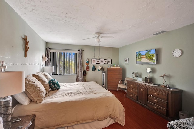 bedroom with dark hardwood / wood-style floors, a textured ceiling, and ceiling fan