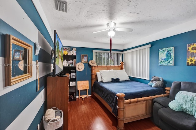 bedroom featuring dark wood-type flooring, a textured ceiling, and ceiling fan