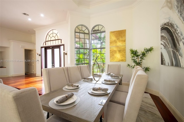 dining room featuring baseboards, crown molding, visible vents, and wood finished floors