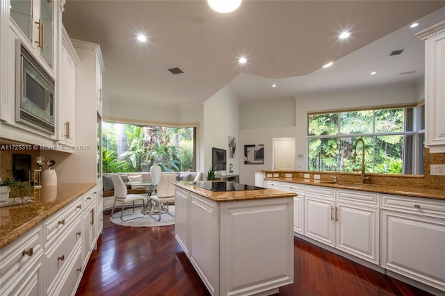 living area with visible vents, baseboards, wood finished floors, a high ceiling, and ornamental molding