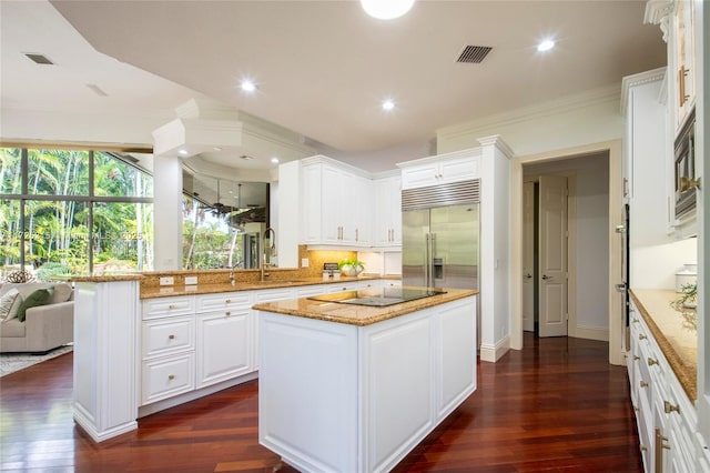 kitchen featuring visible vents, white cabinetry, a kitchen island, light stone countertops, and built in appliances