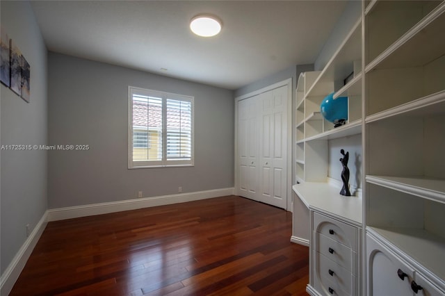 unfurnished bedroom with dark wood-style floors, baseboards, and a closet