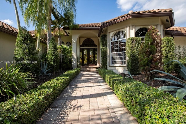 entrance to property with stucco siding, a tile roof, and french doors