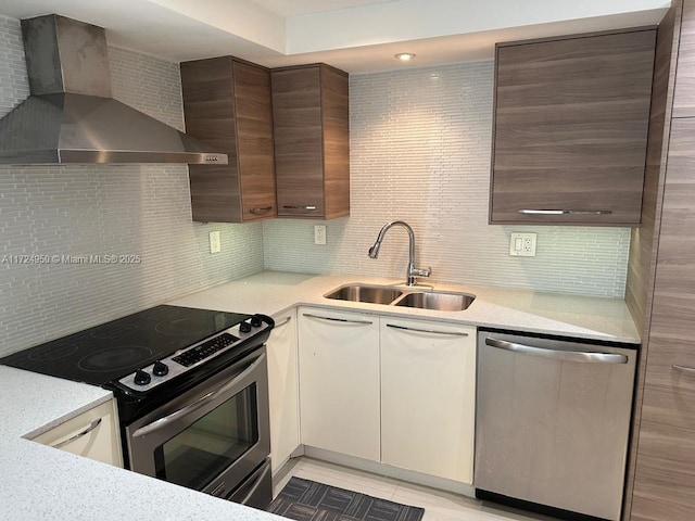 kitchen with wall chimney exhaust hood, stainless steel appliances, backsplash, white cabinetry, and sink