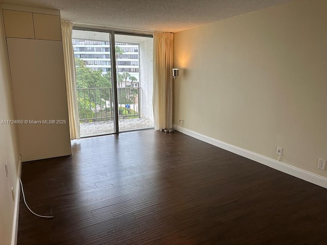 unfurnished room with a textured ceiling, a wall of windows, and dark hardwood / wood-style flooring