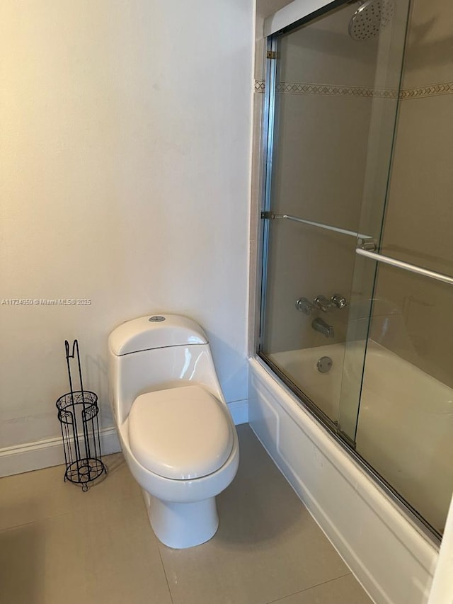 bathroom featuring combined bath / shower with glass door, tile patterned floors, and toilet