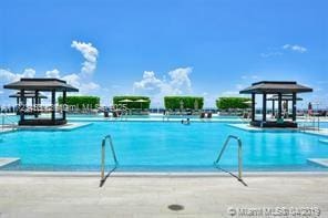 view of swimming pool with a beach view and a water view