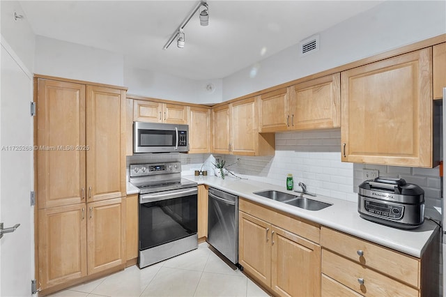 kitchen featuring sink, light brown cabinets, light tile patterned floors, decorative backsplash, and appliances with stainless steel finishes