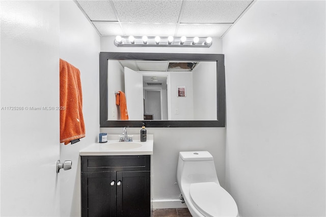 bathroom featuring a paneled ceiling, vanity, and toilet