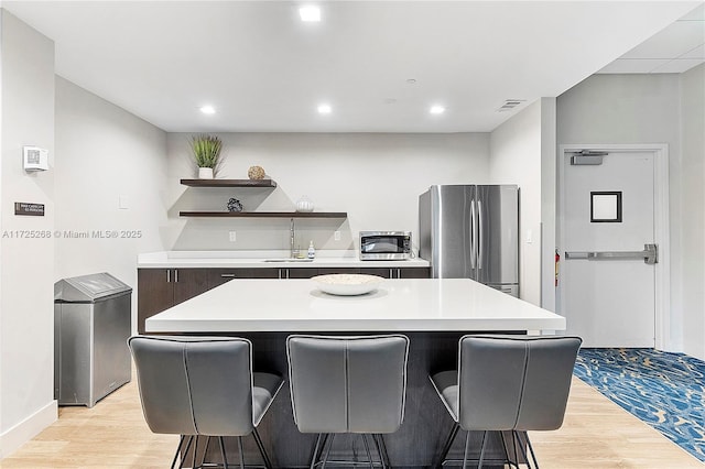 kitchen with sink, light wood-type flooring, a center island, and stainless steel refrigerator