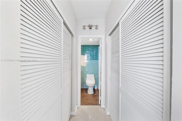 hall with tile walls and light tile patterned flooring