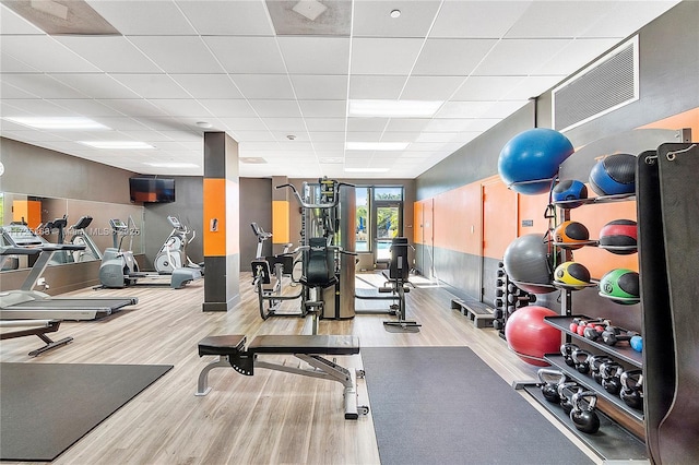 workout area featuring a paneled ceiling and hardwood / wood-style floors