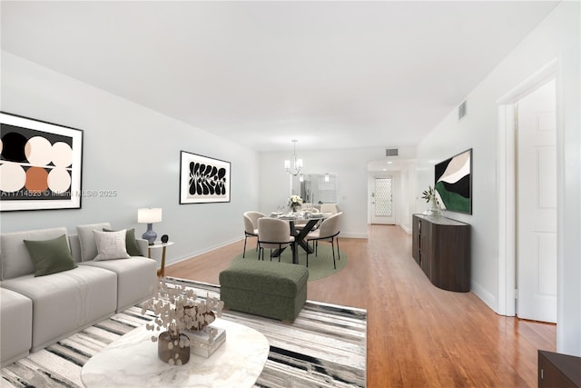 living room with an inviting chandelier and light hardwood / wood-style flooring