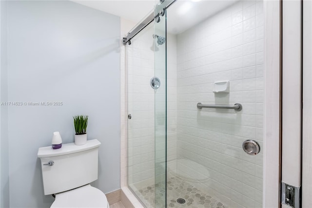 bathroom featuring toilet and a shower with shower door