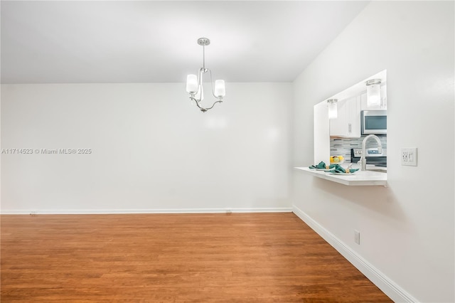 unfurnished dining area with wood-type flooring and a chandelier