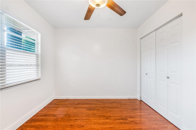 unfurnished bedroom featuring hardwood / wood-style floors, ceiling fan, and a closet