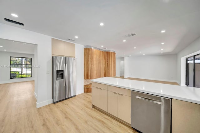 kitchen with appliances with stainless steel finishes, light hardwood / wood-style flooring, and light brown cabinets