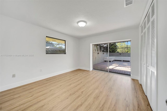 unfurnished room with a textured ceiling and light hardwood / wood-style floors