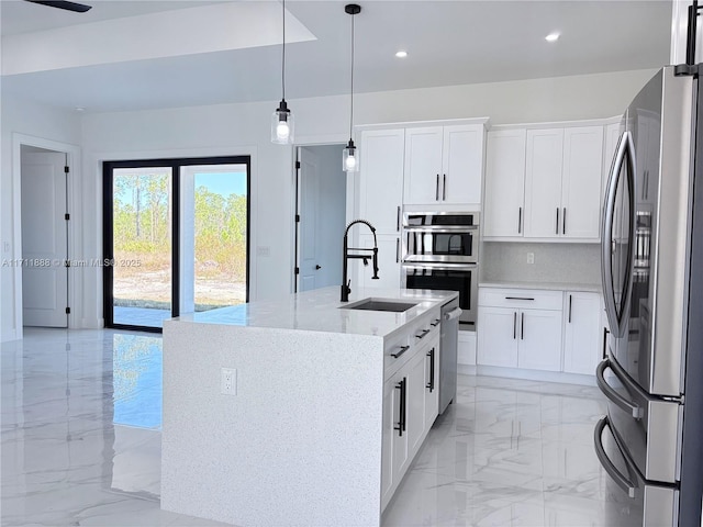 kitchen featuring stainless steel appliances, a center island with sink, white cabinets, and light stone countertops