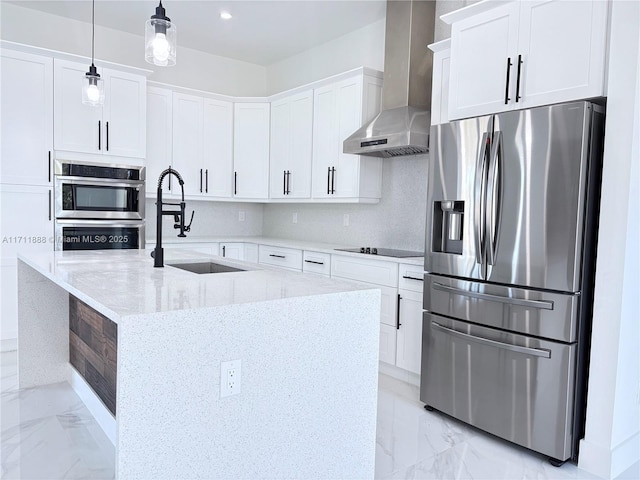 kitchen featuring stainless steel appliances, white cabinets, decorative light fixtures, light stone countertops, and wall chimney range hood