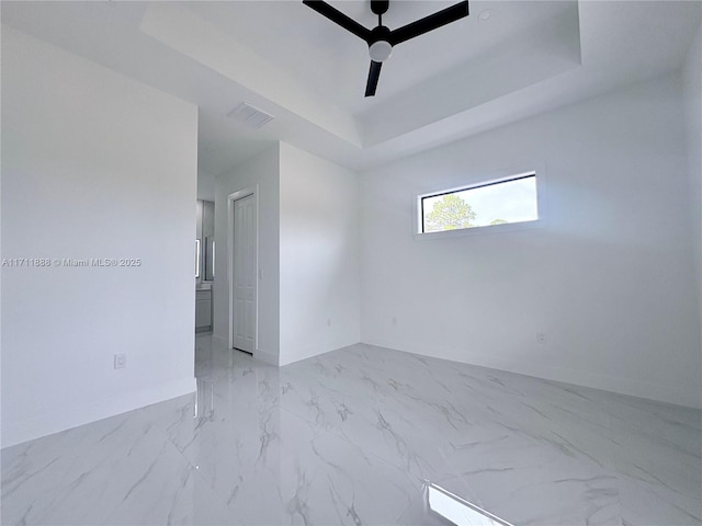 spare room featuring ceiling fan and a raised ceiling