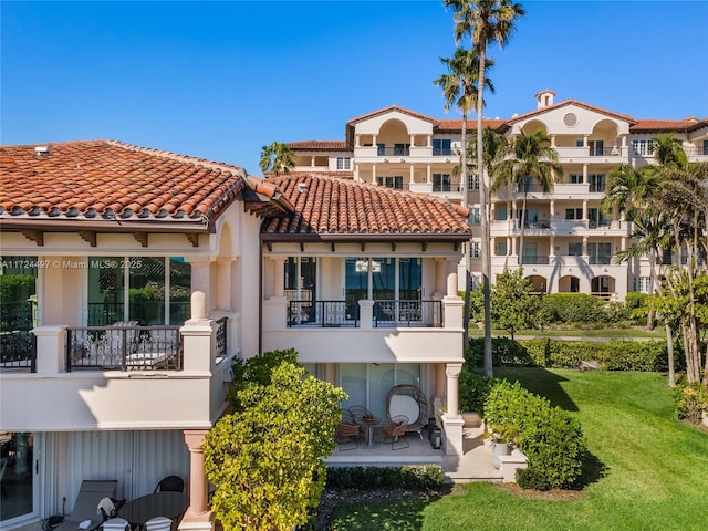 rear view of property with a yard, a balcony, and a patio