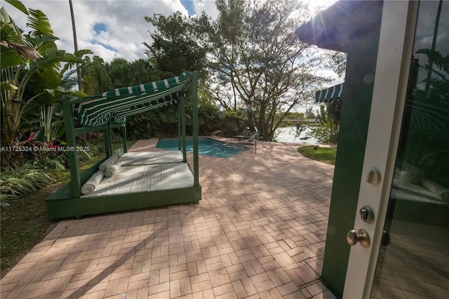 view of swimming pool featuring a patio and a water view