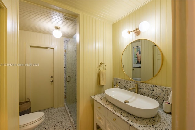 bathroom with vanity, toilet, walk in shower, and wood walls