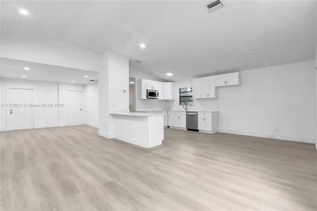 kitchen with white cabinets, vaulted ceiling, light hardwood / wood-style flooring, kitchen peninsula, and appliances with stainless steel finishes