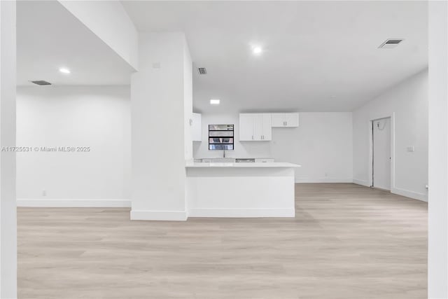 kitchen featuring kitchen peninsula, light hardwood / wood-style flooring, and white cabinetry