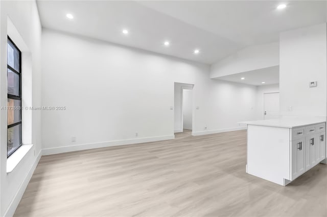 unfurnished living room featuring vaulted ceiling and light hardwood / wood-style flooring