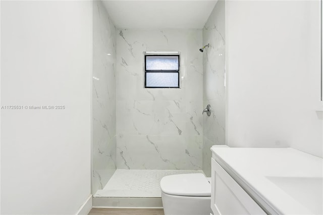 bathroom with a tile shower, vanity, and toilet