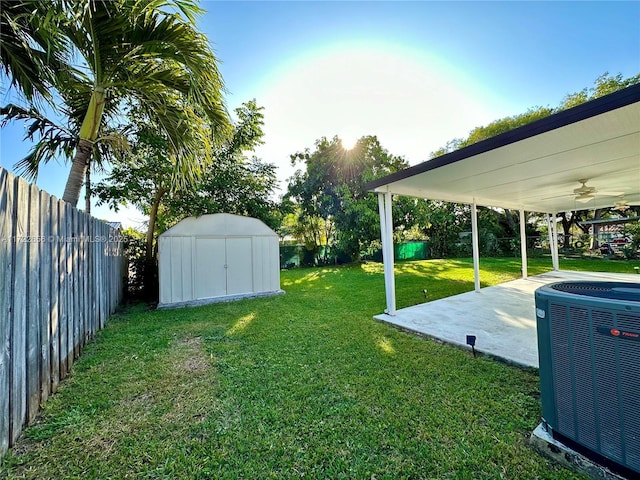 view of yard with ceiling fan, cooling unit, a storage shed, and a patio area