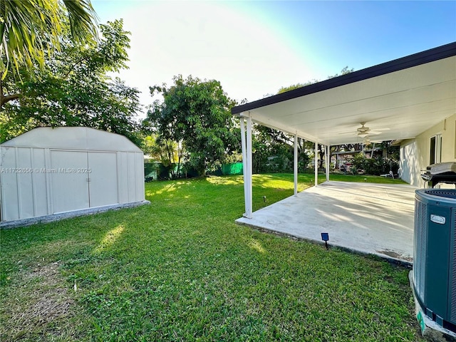 view of yard with ceiling fan, a patio, central AC unit, and a storage shed