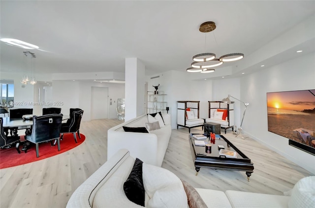 living room with an inviting chandelier and light hardwood / wood-style flooring